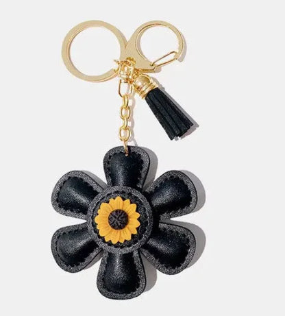 Handmade black leather daisy keychain with yellow center and gold clasp.