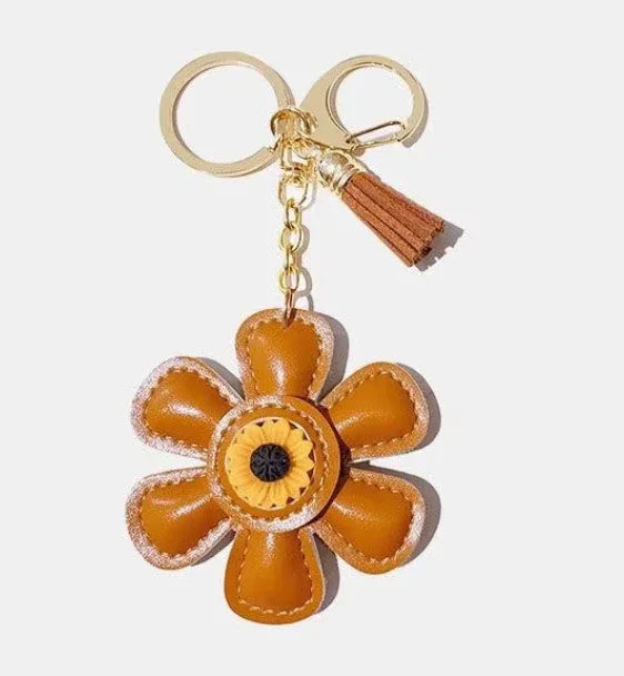 Handmade orange leather daisy keychain with yellow center and gold clasp.