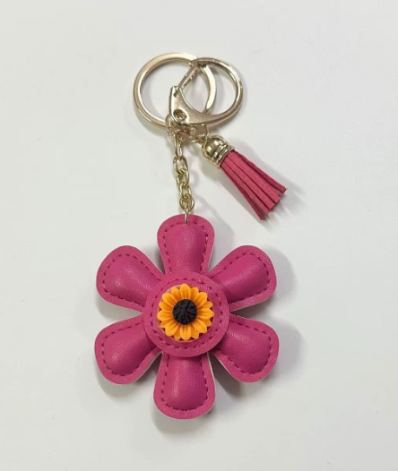 Handmade pink leather daisy keychain with yellow center and gold clasp.
