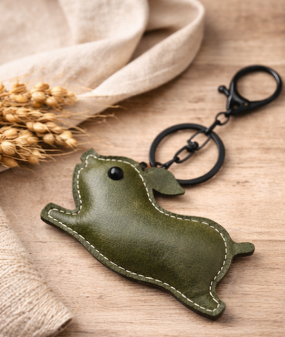 Olive Green Leather Pig Key Chain and Bag Charm with Key ring and clasp on table. 