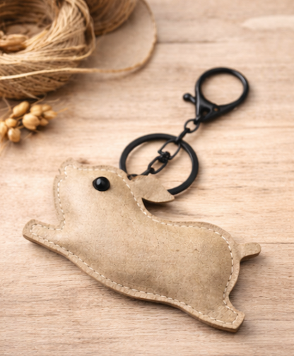 Beige Leather Pig Key Chain and Bag Charm with Key ring and clasp on table. 