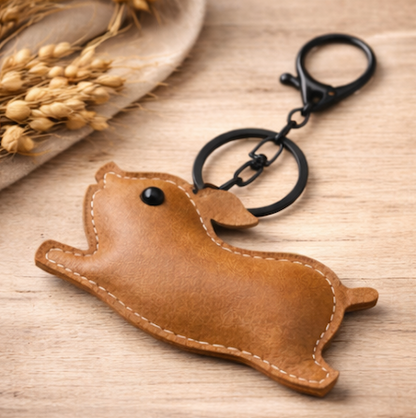 Light Brown Leather Pig Key Chain and Bag Charm with Key ring and clasp on table. 