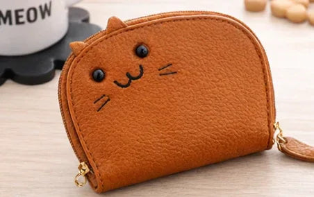 Handcrafted orange cat-shaped leather cardholder with a cute whiskered face and secure gold zipper and tail. 