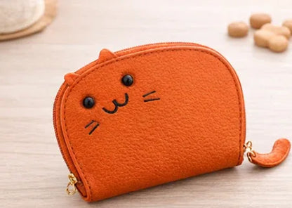 Handcrafted orange cat-shaped leather cardholder with a cute whiskered face and secure gold zipper and tail. 