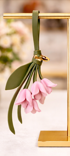Pink Petite Lily Bag Charm  with leather strap on brass display.