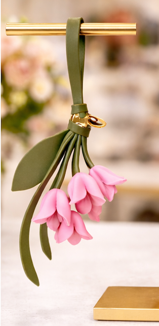 Pink  Petite Lily Bag Charm  with leather strap on brass display.