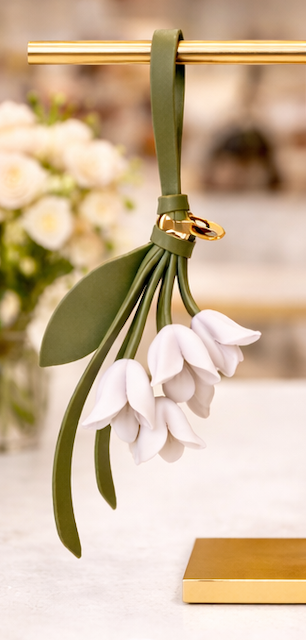 Green  Petite Lily Bag Charm  with leather strap on brass display.