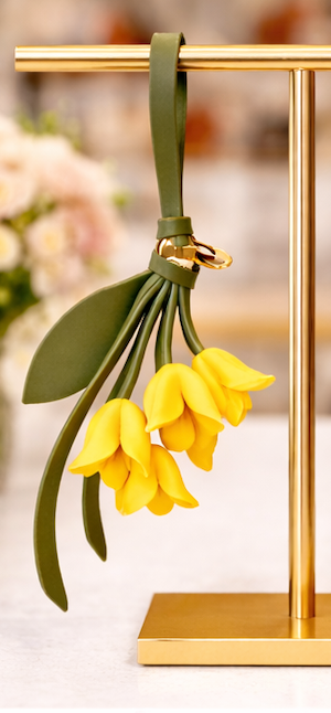 Yellow  Petite Lily Bag Charm  with leather strap on brass display.