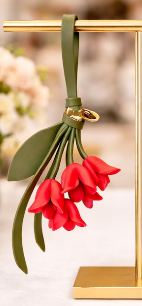 Red Petite Lily Bag Charm  with leather strap on brass display.