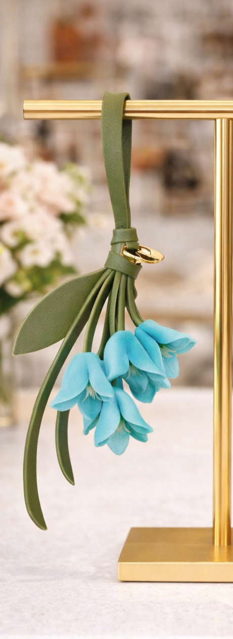 Blue Petite Lily Bag Charm  with leather strap  on brass display.