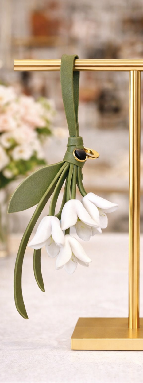 White Petite Lily Bag Charm  with leather strap on brass display.