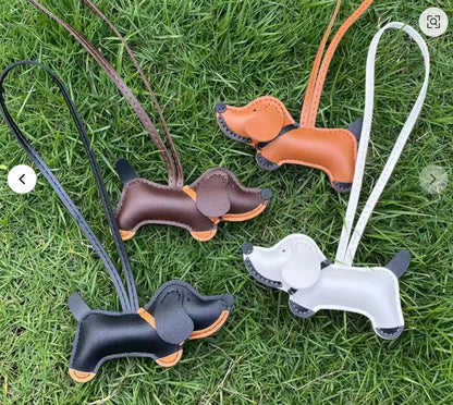 4 different colored Chic Leather Dachshund Bag Charms with leather straps on grass outside. 