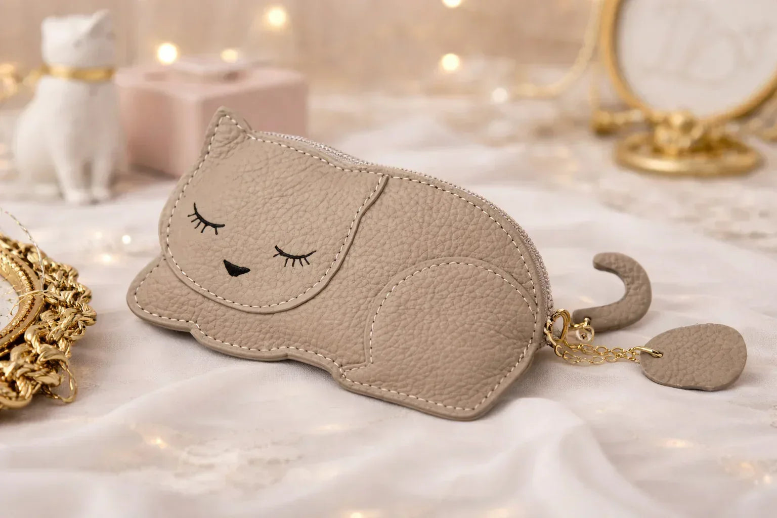 Catnap Cuties sleeping cat leather coin purse in Tan with a zipper closure with tail sitting on table.