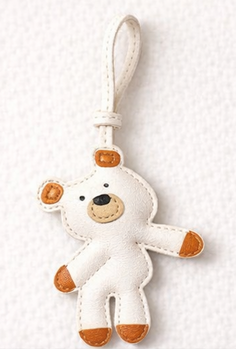 White teddy bear leather bag charm with brown accents on a white background