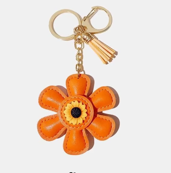 Handmade orange leather daisy keychain with yellow center and gold clasp.