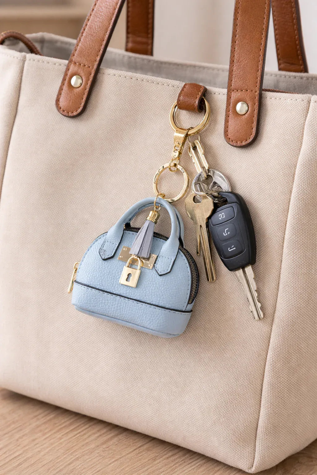 Petite light blue Leather Purse Lock & Key Bag Charm with key ring on a tan purse with keys connected to show size and look.