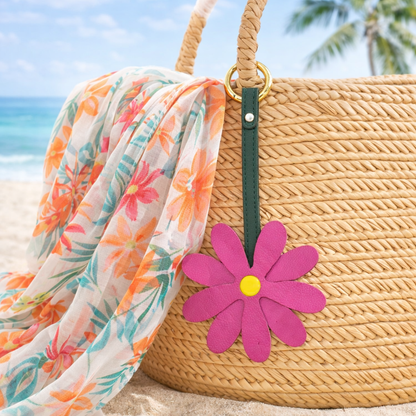 Pink Petal Pop Bag Charm on a straw bag with scarf at the beach. 