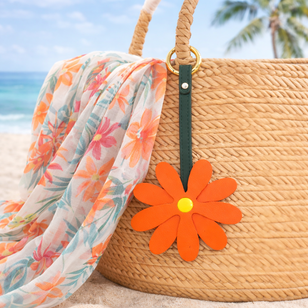 Coral Petal Pop Bag Charm on a straw bag with scarf at the beach. 