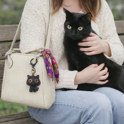video of woman holding a purse with black leather cat keychain attached