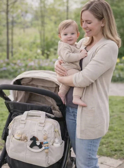 Video of woman holding baby with Black Rockabye Keepsake Horse Charm on white diaper bag on stroller. 
