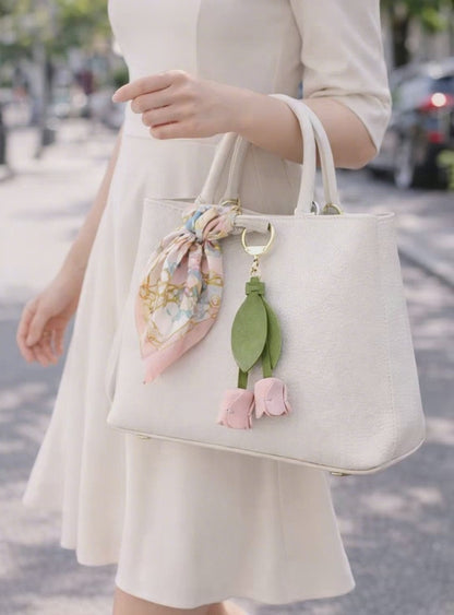Video of Woman walking holding a white purse with a white Sweetheart Tulip Bag Charm with key ring. 